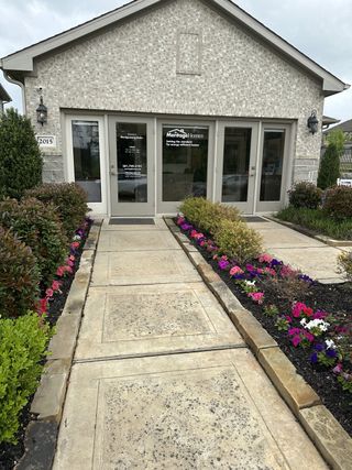 Street view Charming entrance with flourishing flowers at Montgomery Oaks by Meritage Homes in Conroe, TX.