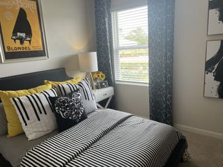 A chic bedroom with a music-themed decor, striped bedding, abstract art, and ample natural light.