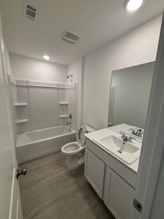 Modern bathroom with sleek white fixtures, a spacious vanity, and wood-style flooring for a clean, contemporary feel.