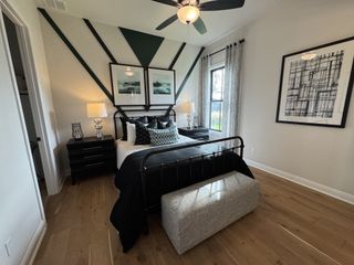 A stylish bedroom with geometric wall art, modern lighting, and a cozy bed, featuring light wood flooring and elegant decor.