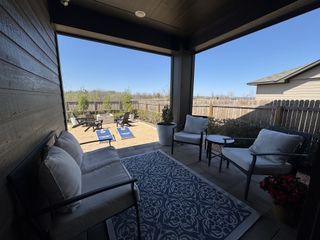 A cozy patio with cushioned seating, patterned rug, and outdoor game setup, perfect for relaxation and entertainment.