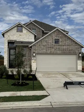 Street view A beautiful brick and stone house with a neat lawn in Santa Rita Ranch by Perry Homes (Liberty Hill, TX).