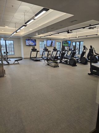 Community Amenities A bright and inviting gym featuring treadmills, ellipticals, and strength training equipment with scenic views.