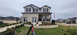 Charming two-story home with stone facade and lush landscaping in Hunter's Ranch by CastleRock Communities (San Antonio, TX).