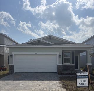 Single-story home with a white garage, stone accents, and a front porch. 