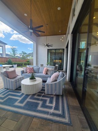 Chic outdoor patio with cozy seating, modern fans, and vibrant decor under a wooden ceiling. Ideal for relaxing and entertaining.
