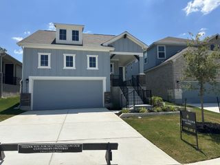 A modern grey home with a spacious driveway and landscaped front yard in Avondale by Scott Felder Homes (San Antonio, TX).