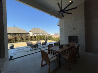 Model Home A spacious outdoor patio with a wooden dining set, ceiling fan, and cozy seating area, perfect for enjoying sunny days.