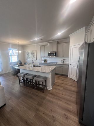 Modern kitchen with granite island, sleek cabinetry, and wood floors, offering ample seating and a cozy dining area.