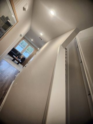 A modern hallway leading to a cozy living area with wood flooring and bright windows, creating a welcoming atmosphere.
