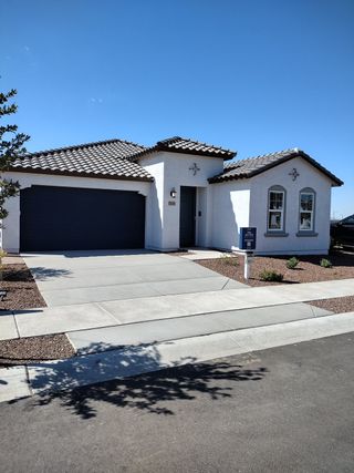 A charming white home with a tiled roof and landscaped yard in El Cidro Signature by Lennar (Goodyear, AZ).
