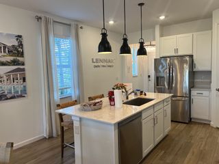 A modern kitchen with stainless steel appliances, pendant lighting, and a large island with a marble countertop.