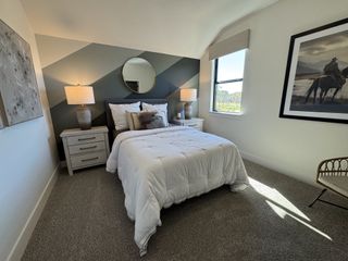 A cozy bedroom with a geometric accent wall, elegant bedside lamps, and a large window inviting natural light.