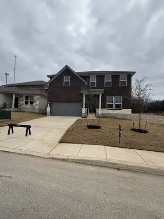 Street view A modern brick home with a two-car garage and a landscaped yard in San Antonio, TX.