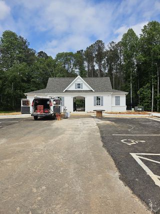 Street view A charming white home with a gable roof nestled in Wildwood Place by Traton Homes in Powder Springs, GA.