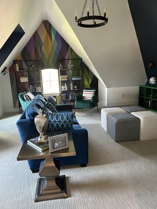 A cozy loft with a geometric accent wall, blue and green seating, and modern decor.