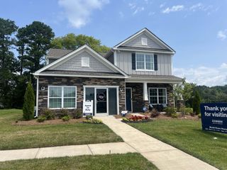 A charming stone-accented home with a manicured lawn in Adair Woods by D.R. Horton (Davidson, NC).