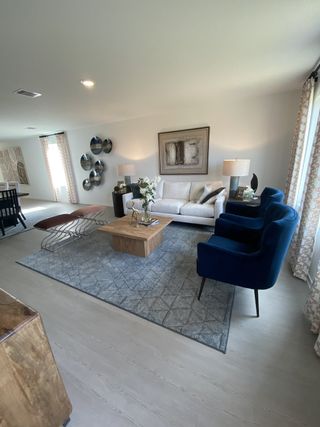 Model Home A cozy living room with elegant décor, featuring a plush sofa, blue chairs, wooden coffee table, and stylish accents.