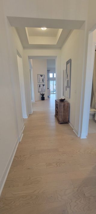 Model Home A welcoming foyer with light wood flooring and architectural details, leading to an open living space in a Stillwater Ranch home by Coventry Homes (San Antonio, TX).