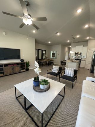 Model Home An inviting living room with a sleek ceiling fan, marble coffee table, and open kitchen vista offers modern comfort.