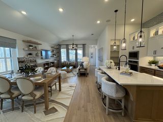 A contemporary open-concept living area with a cozy dining space, sleek kitchen island, and elegant lighting.