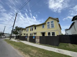 Street view A charming yellow townhome in Koenig Townhomes by Milestone Community Builders, located in Austin, TX.