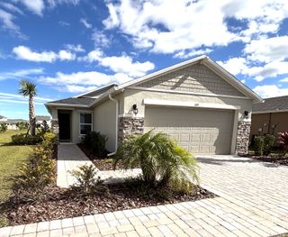 Charming stone-accented home with a landscaped front yard in Gardens at Waterstone III by KB Home (Palm Bay, FL).