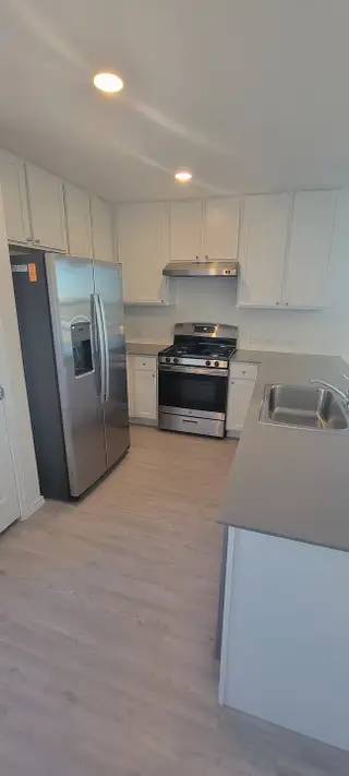 A modern kitchen with sleek stainless steel appliances, bright cabinetry, and a spacious countertop.