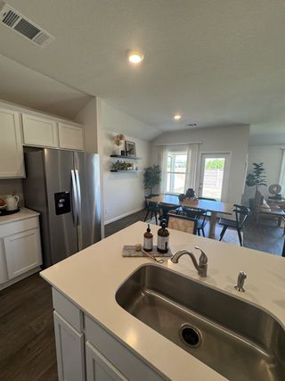 Modern kitchen with a sleek island sink, stainless steel appliances, and dining area, featuring abundant natural light.