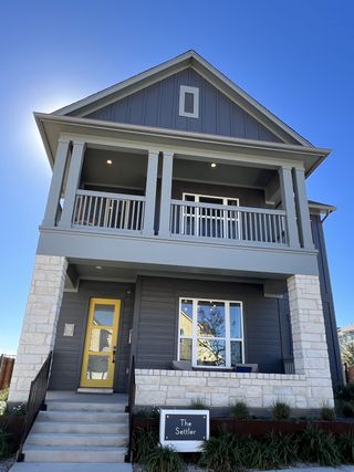 Street view A stylish modern home with a charming second-story balcony and bold yellow door in Goodnight Ranch by David Weekley Homes (Austin, TX).
