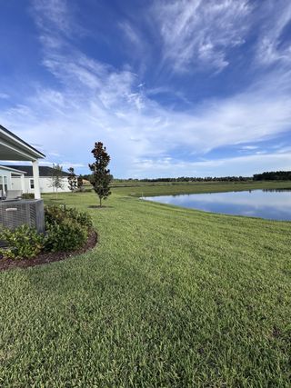 Community Amenities A serene landscape with a clear pond and lush greenery in Amberly by Dream Finders Homes (Green Cove Springs, FL).