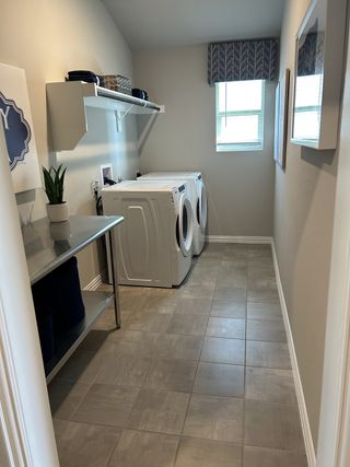 Model Home A spacious laundry room with modern appliances, ample shelving, and natural light, creating a functional and organized space.