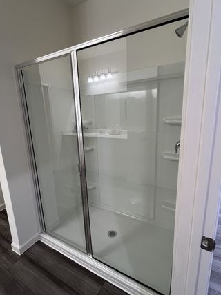 A sleek glass-enclosed shower with chrome fixtures and wood-style flooring.