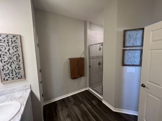 A modern bathroom featuring a sleek glass shower, intricate wall art, and elegant dark wood flooring.