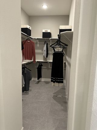 Model Home A spacious walk-in closet featuring organized shelving, clothing racks, and overhead lighting for a modern lifestyle.