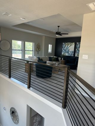 A modern living area featuring a spacious layout, neutral decor, and cozy seating with elegant railings.