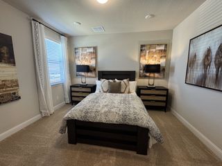 Model Home Cozy bedroom with a stylish bed, patterned bedding, dark wood furniture, and modern artwork.