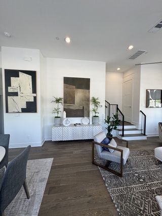 A modern living area featuring abstract art, a textured console, stylish seating, and a patterned rug on wood flooring.