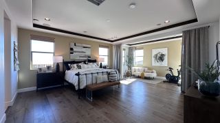 A spacious master bedroom with hardwood floors, cozy sitting area, and modern decor. Perfect for relaxation and comfort.