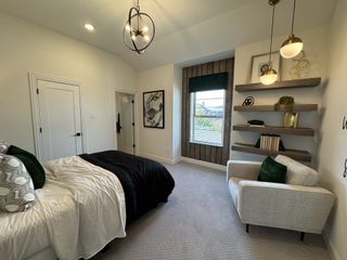 Model Home A cozy bedroom featuring elegant lighting, modern wall art, and sleek floating shelves, creating a stylish and inviting ambiance.