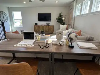 A contemporary living space with a stylish desk, comfy sofa, and modern décor accents, featuring natural light and chic design.