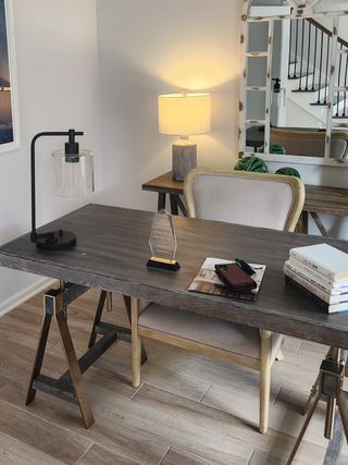 Model Home A chic home office featuring a rustic wood desk, stylish lamps, and a decorative wall mirror, creating a cozy workspace.