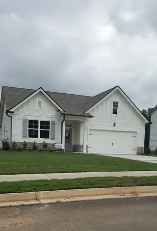 A charming white home with stone accents and lush lawn in Fairhaven by D.R. Horton (Lithia Springs, GA).