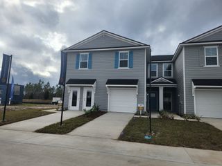 Street view A modern gray home with blue shutters and a tidy lawn in Atlantis Pointe by Dream Finders Homes (Middleburg, FL).