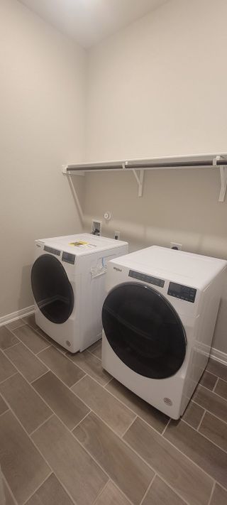 Model Home A sleek laundry room with modern appliances, tile flooring, and a convenient storage shelf.
