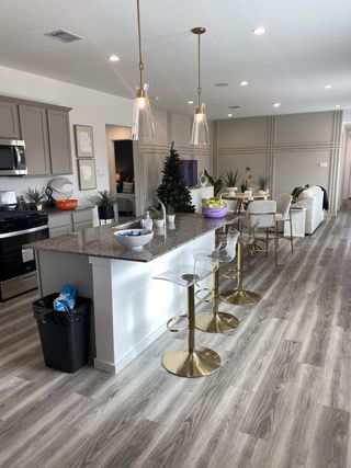 Model Home A modern open-concept kitchen with gray cabinets, pendant lighting, and a sleek island with gold barstools.