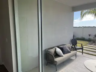 A cozy outdoor patio with a wicker sofa, plush cushions, and manicured garden views.