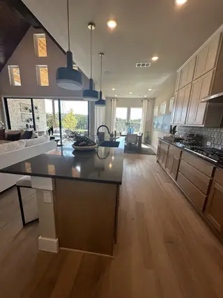 Model Home A modern kitchen with sleek pendant lighting, wood floors, and ample natural light.