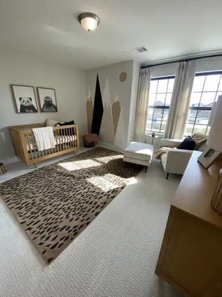 Model Home A charming nursery with animal artwork, playful wall design, cozy crib, and natural light streaming through large windows.