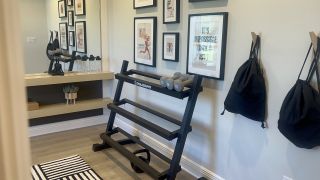 A sleek home gym with motivational artwork, a weight rack, and modern shelves for a chic workout environment.